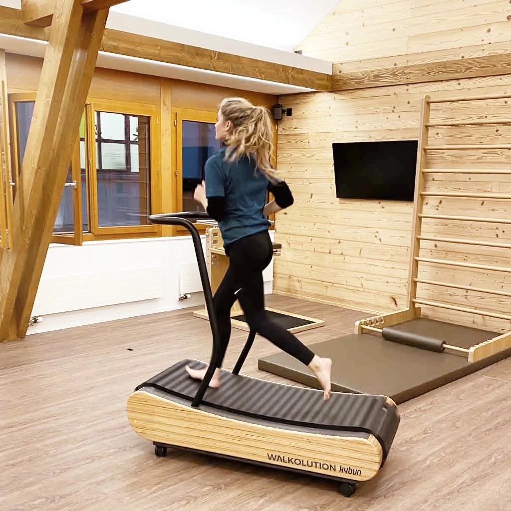 Young woman running on soft wooden treadmill, barefoot treadmill Walkolution USA
