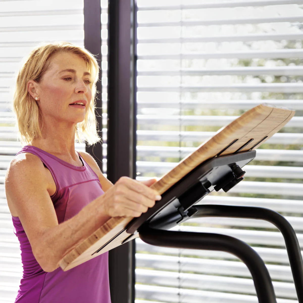 Woman removes table attachment from treadmill desk Walkolution USA